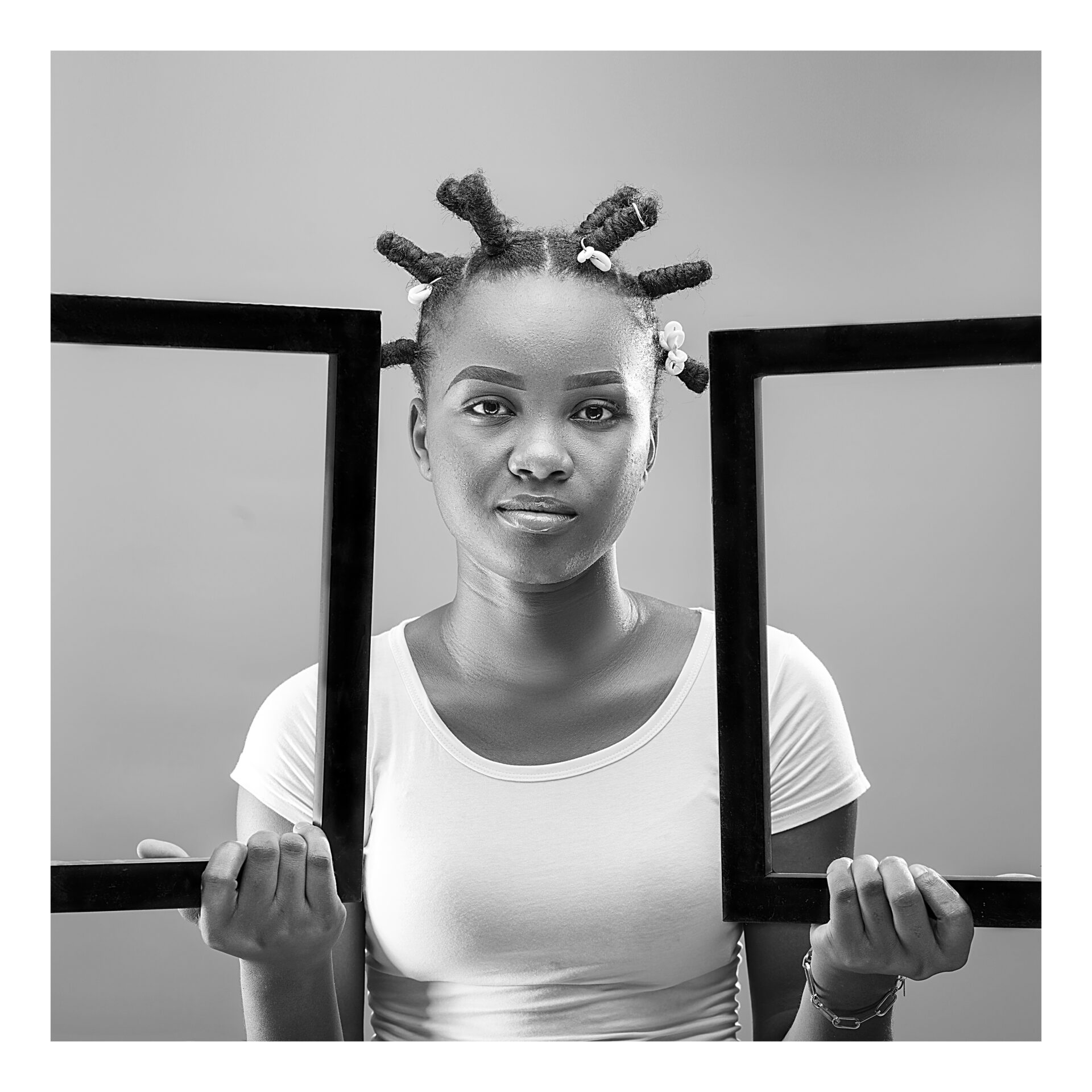 une-femme-noire-dans-une-image-en-portrait-en-noir-et-blanc-qui-porte-des-cadres-avec-des-tresses-africaines