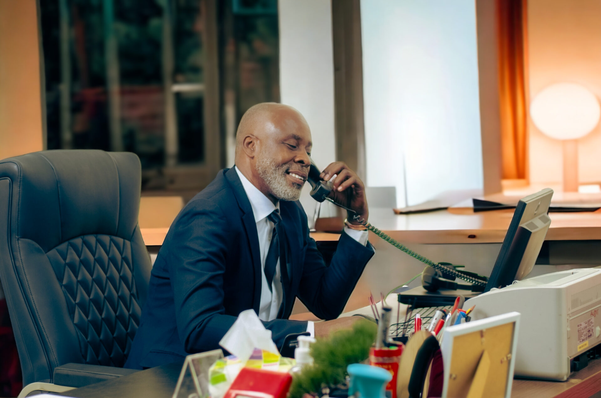 un-homme-daffaires-noir-africain-qui-est-dans-son-bureau-parlant-au-telephone-et-qui-sourit