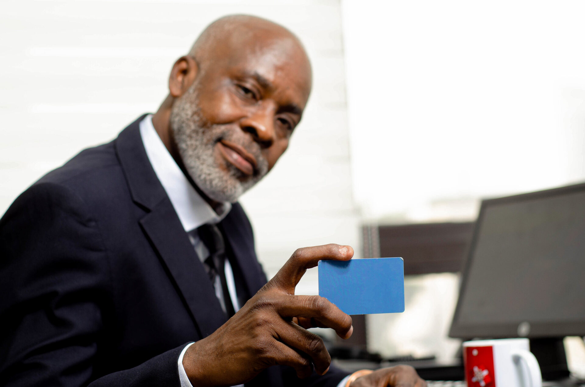 un-homme-noir-professionnel-qui-tient-une-carte-bancaire-assis-a-son-bureau-devant-son-ordinateur