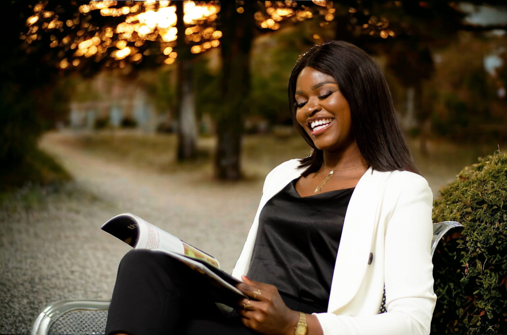 jeune-femme-noire-africaine-assise-sir-un-banc-en-train-de-lire-un-magazine-en-souriant