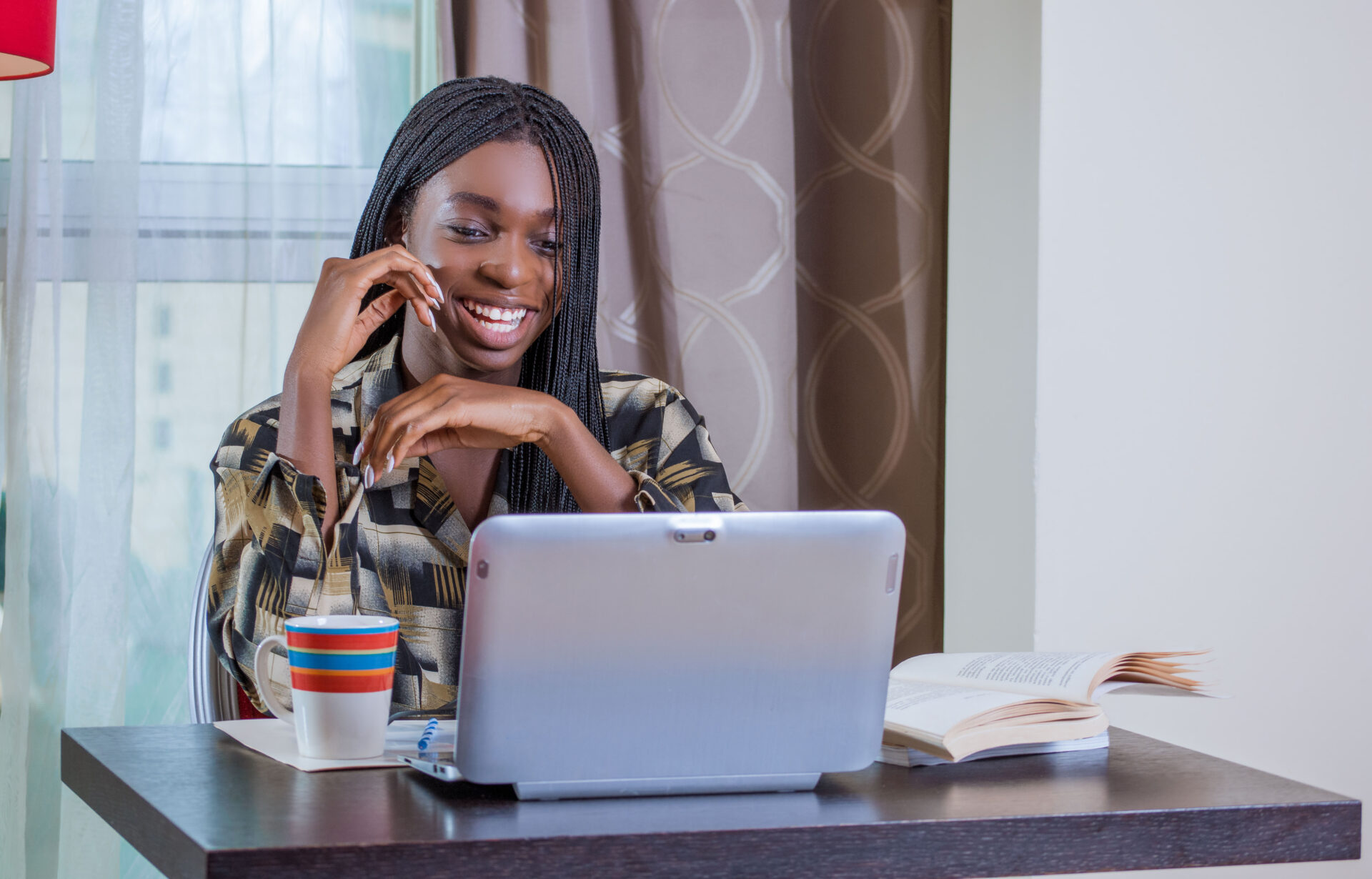 une-etudiante-ou-eleve-assise-a-son-bureau-qui-regarde-sur-son-ordinateur-en-souriant